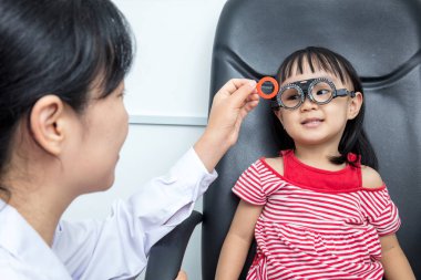 Asyalı küçük Çinli kız yapıyor gözleri bir sınava ophthalmolog