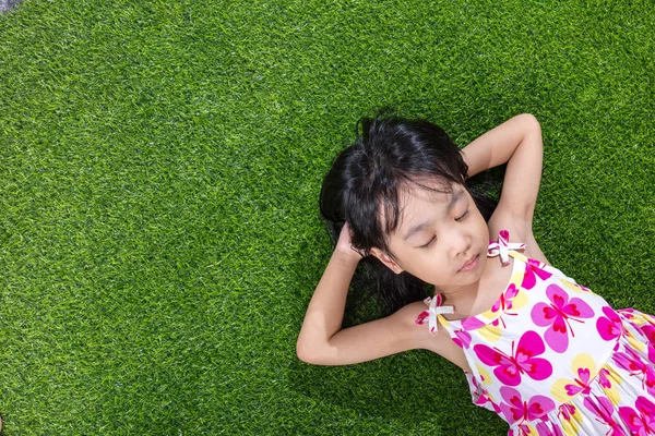 Asiática chinesa menina deitada na grama — Fotografia de Stock