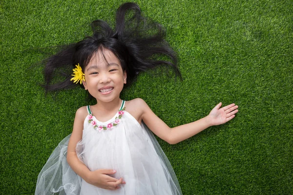 Asyalı Çinli küçük kız çiçek ile çim üzerinde yalan — Stok fotoğraf