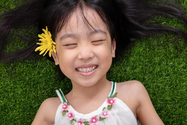 Asiática china niña mintiendo en la hierba con flor — Foto de Stock