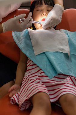 Asyalı Çinli küçük kız diş çekimi için uzanarak