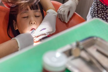 Asyalı Çinli küçük kız diş çekimi için uzanarak