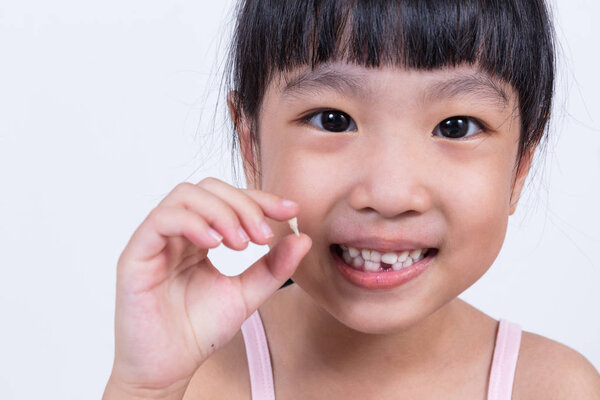 Asian Chinese little girl holding her missing tooth