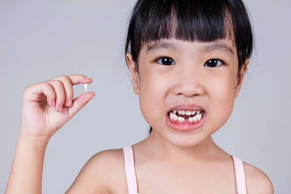 Asiatiska kinesiska liten flicka håller hennes saknad tand — Stockfoto