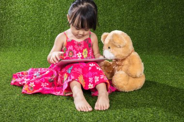 Asyalı Çinli küçük kız tablet bilgisayar teddy ile oynarken bea