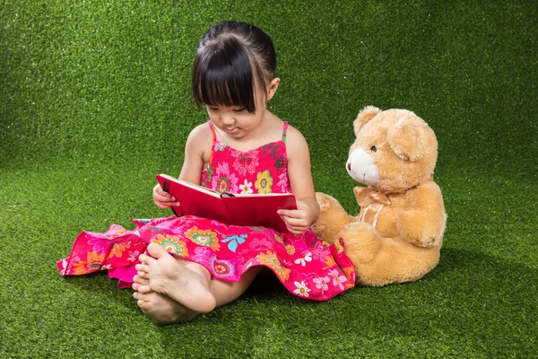 Asiática china niña leyendo libro con osito de peluche —  Fotos de Stock