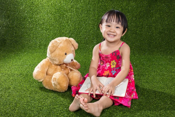 Asiática china niña leyendo libro con osito de peluche —  Fotos de Stock