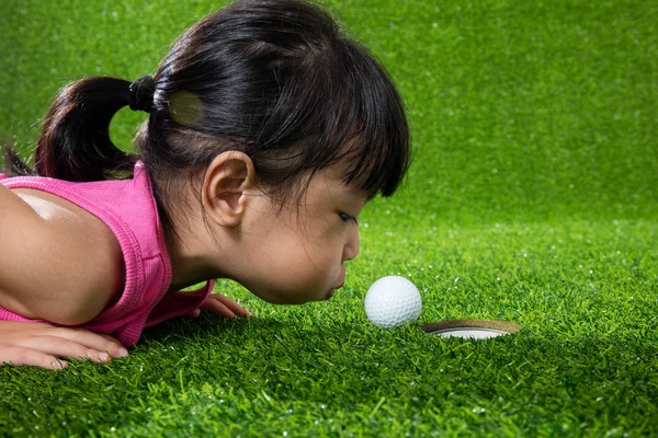 Asiatisch chinesisch klein mädchen blowing die ball in ein loch — Stockfoto