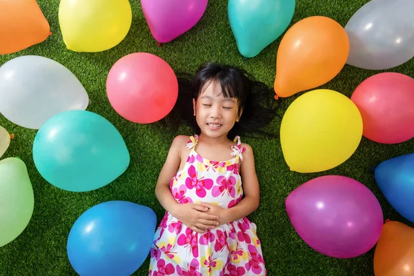 アジアの中国の女の子がカラフルな balloo の間で草の上に横たわる — ストック写真