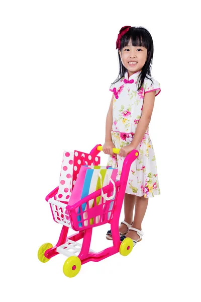 亚洲的中国小女孩穿着旗袍推玩具手推车 — 图库照片