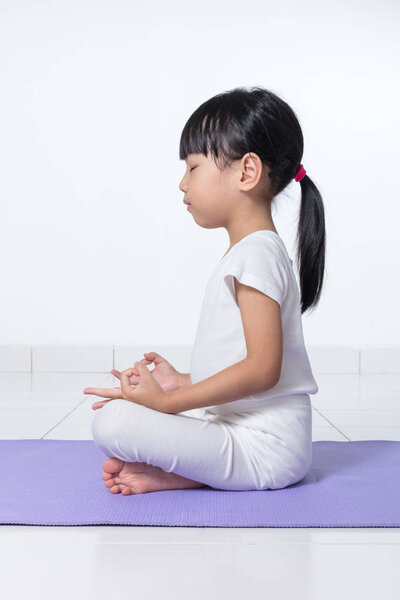 Азиатская маленькая девочка практикующая йогу
