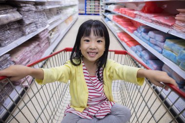 Mutlu Asyalı küçük Çin alışveriş sepeti içinde oturan kız