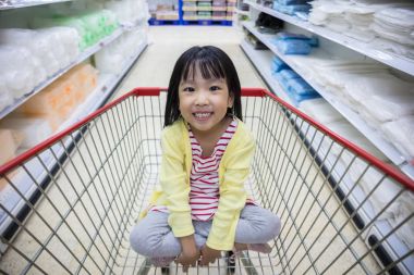 Mutlu Asyalı küçük Çin alışveriş sepeti içinde oturan kız