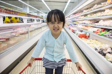 Mutlu Asyalı küçük Çin alışveriş sepeti içinde oturan kız