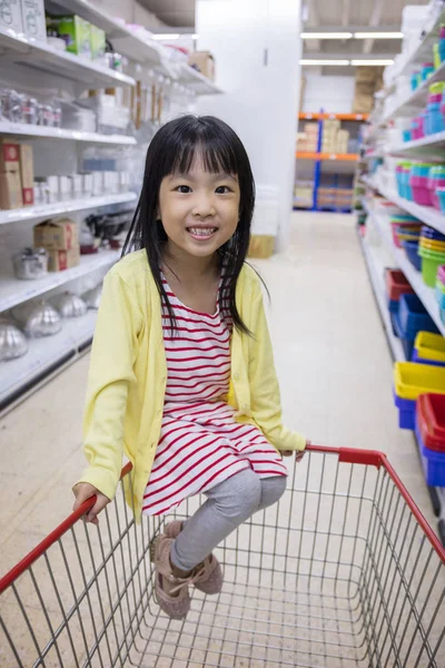 Mutlu Asyalı küçük Çin alışveriş sepeti içinde oturan kız