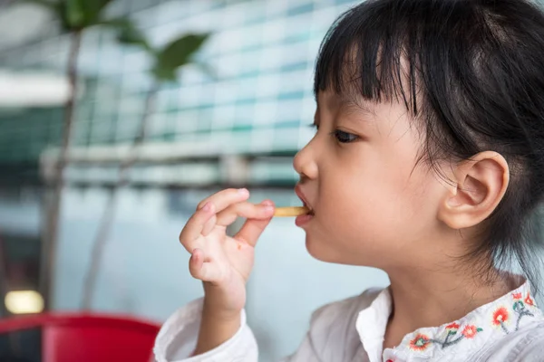 Asiatiska kinesiska lilla flicka äter pommes frites — Stockfoto