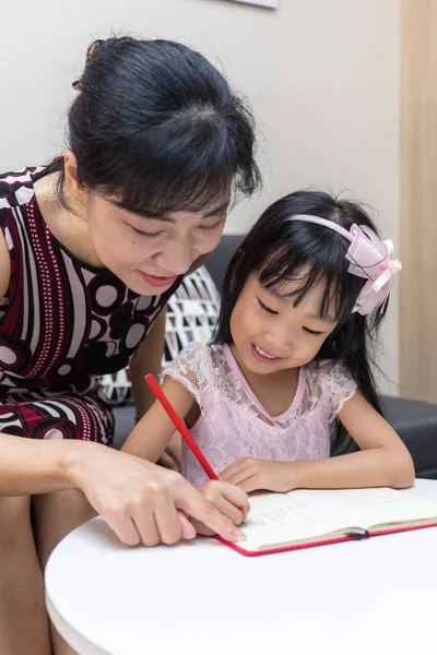 Asian Chinese mother teaching daughter doing homework