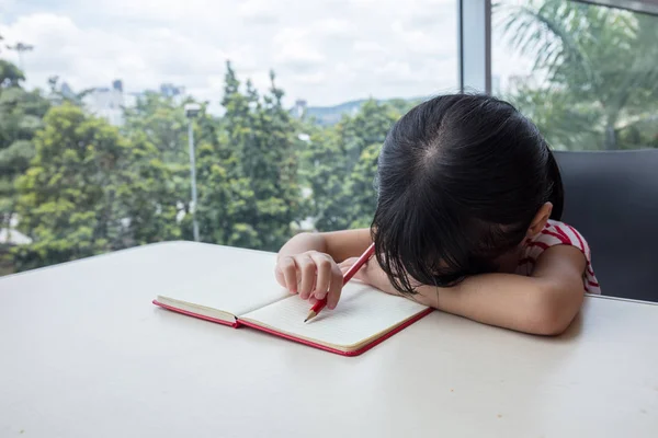 Boring asian little Chinese girl writing homework