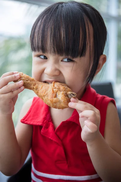 Asiatiska kinesiska lilla flicka äter stekt kyckling — Stockfoto