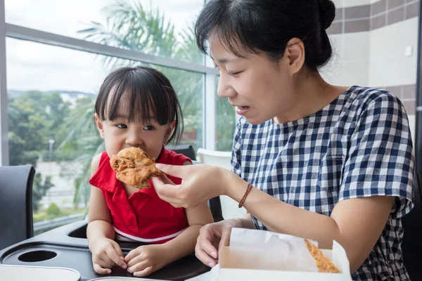 Asian Chinese mother and daughter eating fried chicken — Stock Photo, Image