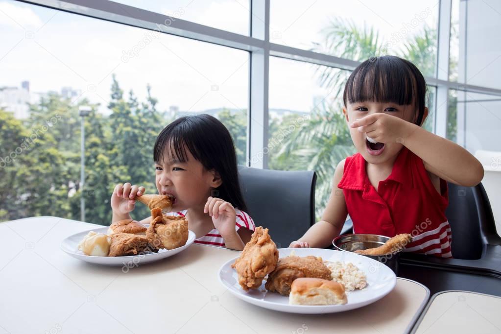 Asian Chinese little girls eating fried chicken