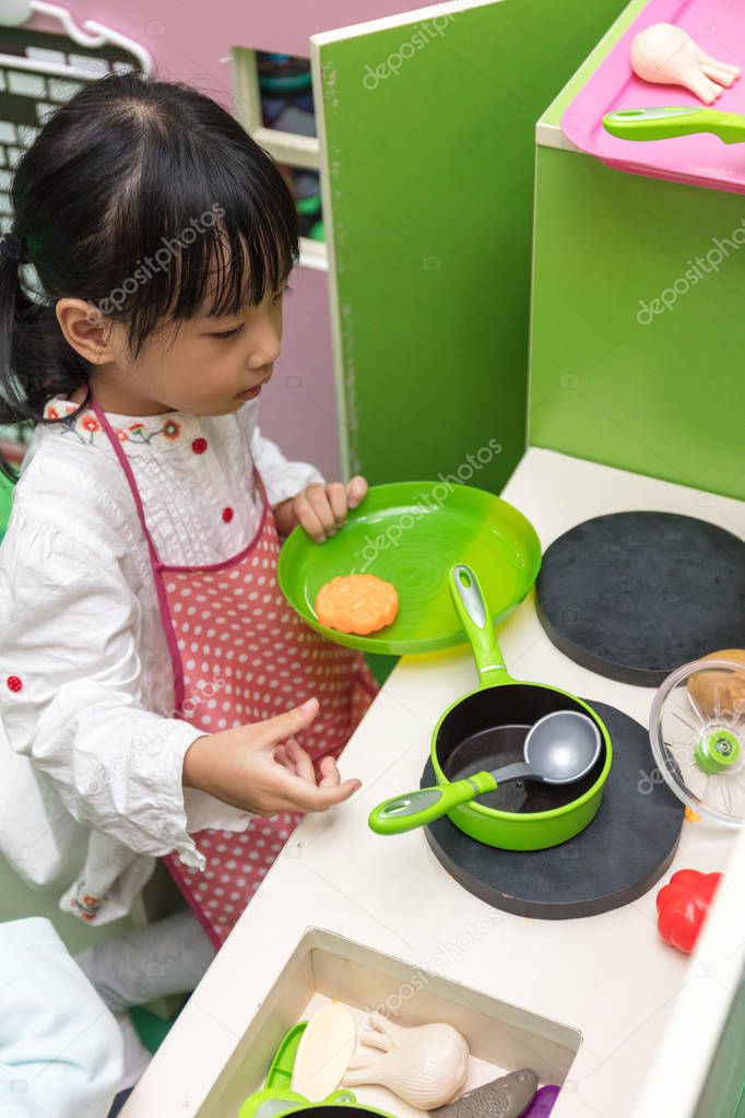 Asian Chinese little girl role-playing at kitchen