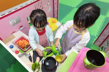 Asian Chinese little girls role-playing at kitchen clipart