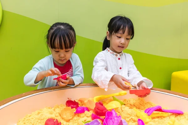 Asiatiska kinesiska lillasyster spelar Kinetic Sand — Stockfoto