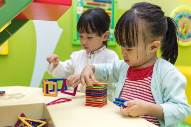 Asyalı Çinli küçük kızlar renkli mıknatıs plastik blok oynarken
