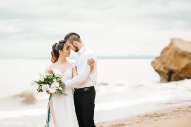 Genç çift damat ile gelini kumlu bir plaj üzerinde