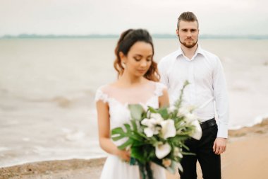 Genç çift damat ile gelini kumlu bir plaj üzerinde