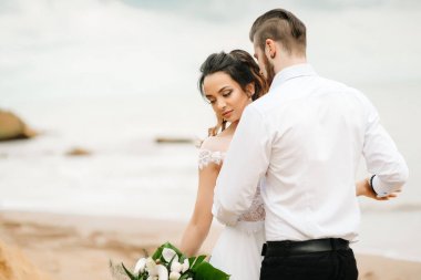 Genç çift damat ile gelini kumlu bir plaj üzerinde