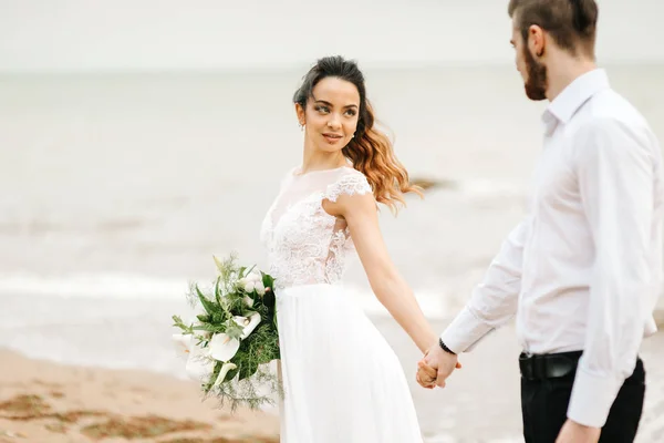 Noivo de par jovem com a noiva em uma praia arenosa — Fotografia de Stock