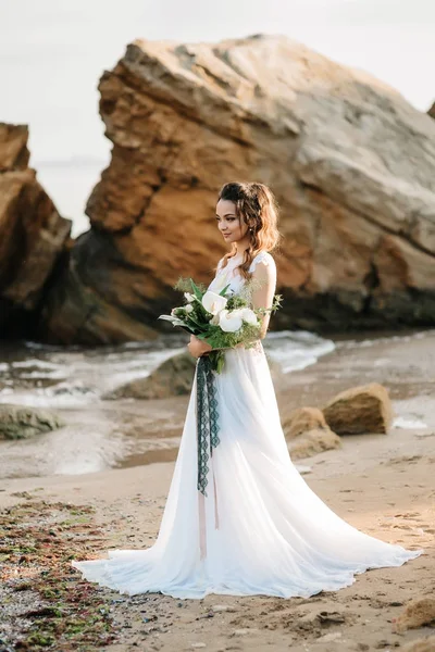 Невеста со свадебным букетом на берегу моря — стоковое фото