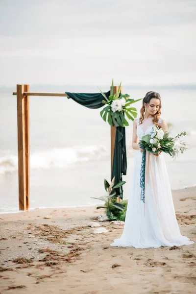 Novia con un ramo de bodas en la orilla del mar —  Fotos de Stock