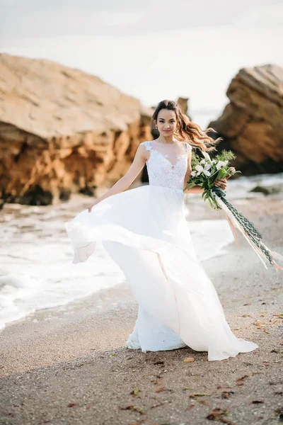 Sposa con un bouquet da sposa sulla riva del mare — Foto Stock