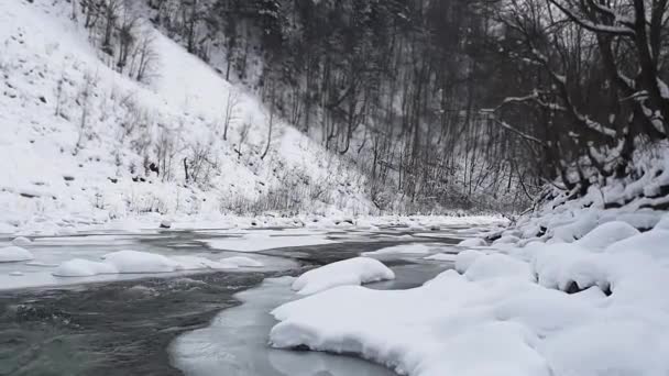 une rivière d'hiver avec une cascade et un rivage glacé, des ruisseaux rapides d'eau de fonte 