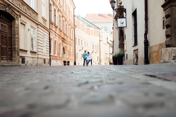 一个男人和一个女孩早上愉快地在老欧洲的空荡荡的街上散步 — 图库照片