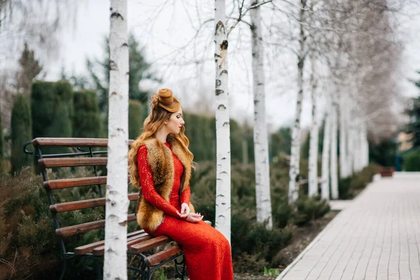 Jovem Com Cabelo Vermelho Vestido Vermelho Brilhante Banco Parque Vazio — Fotografia de Stock