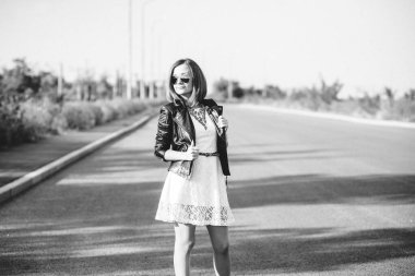 Siyah ceketli, mavi gözlüklü, gri yollu, kızıl saçlı kız.