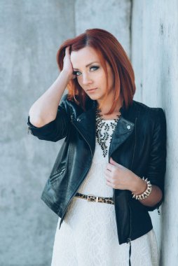 Siyah ceketli, mavi gözlüklü, gri yollu, kızıl saçlı kız.