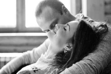 Erkek ve kız pencerenin yanındaki evde. Karlı bir manzaraya bakıyor.