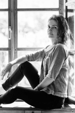 Pencerenin yanındaki evde karlı manzaraya bakan bir kız.