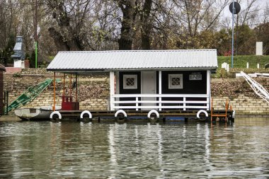 Nehir kıyısına demirlemiş bir sal evi.