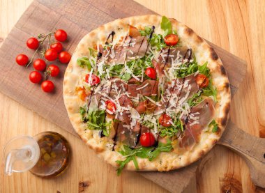 Kurutulmuş jambon pizza, roket bırakır, domates ve Parmesan peyniri 