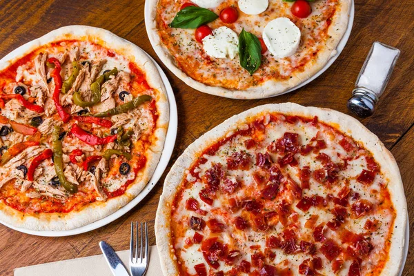 Verscheidene verschillende pizza's op een houten restaurant tafel. — Stockfoto