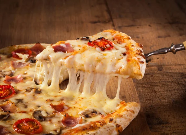 A slice of hot pizza just from the oven with melted cheese dripping — Stock Photo, Image