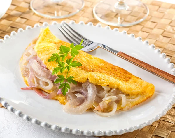 Delicious egg omelet filled with fried onions on a plate. — Stock Photo, Image
