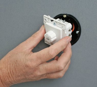 Duvardaki bir prize dimmer anahtarı yükleme elektrikçi