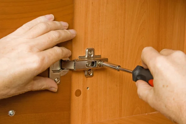Carpinteiro ajustando uma dobradiça da porta do armário — Fotografia de Stock